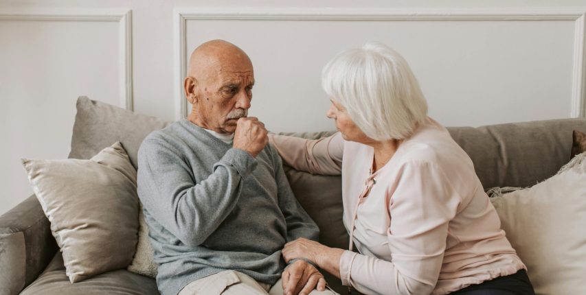 pexels-photo-5790716-5790716 An elderly woman comforts a man coughing on a couch, showcasing care and affection.